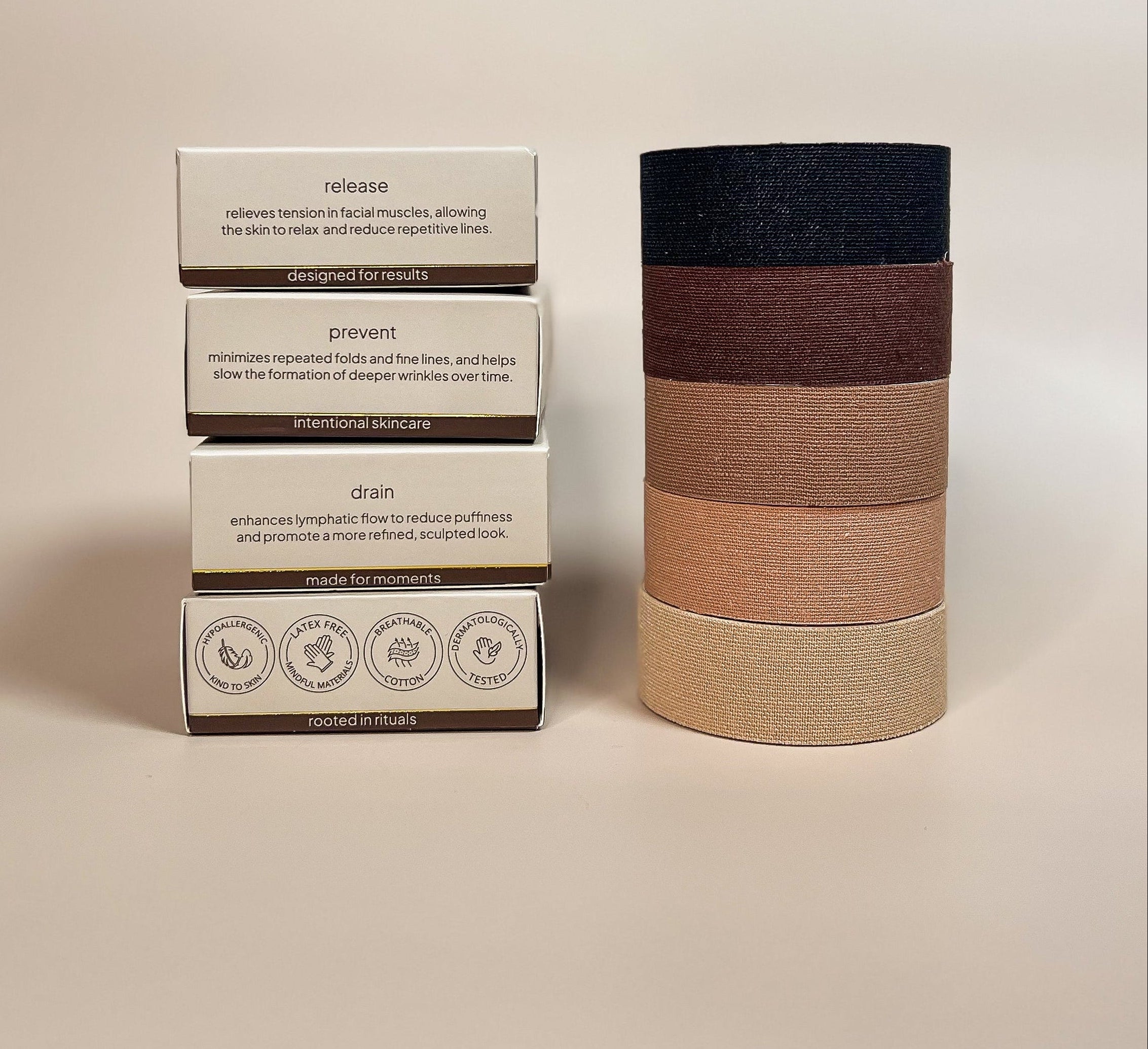 Aluma Contour face tape for sleep packaging stacked on the release box with product benefits visible, next to a tower of tape rolls in four shades.