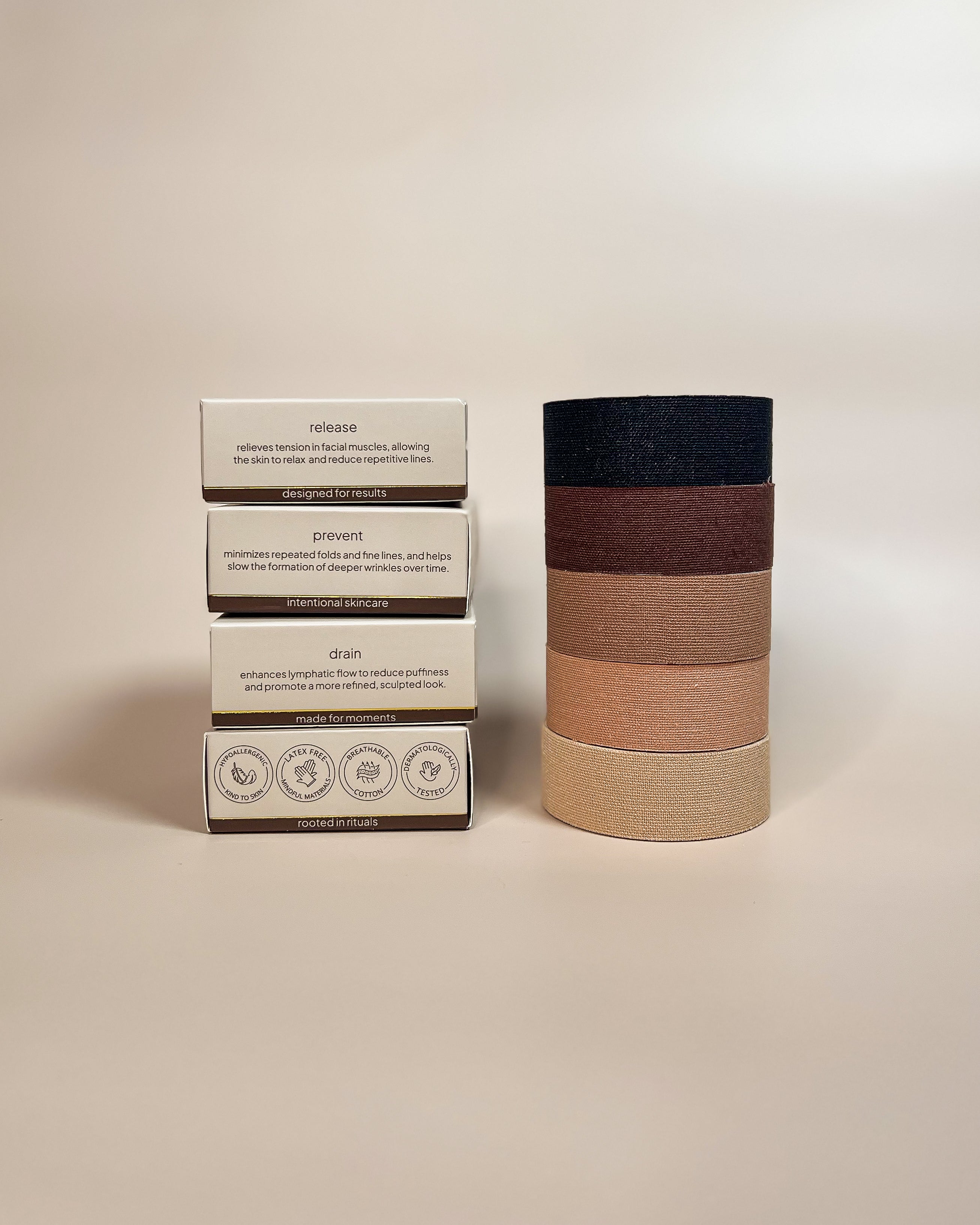 Aluma Contour face tape for sleep packaging stacked on the release box with product benefits visible, next to a tower of tape rolls in four shades.