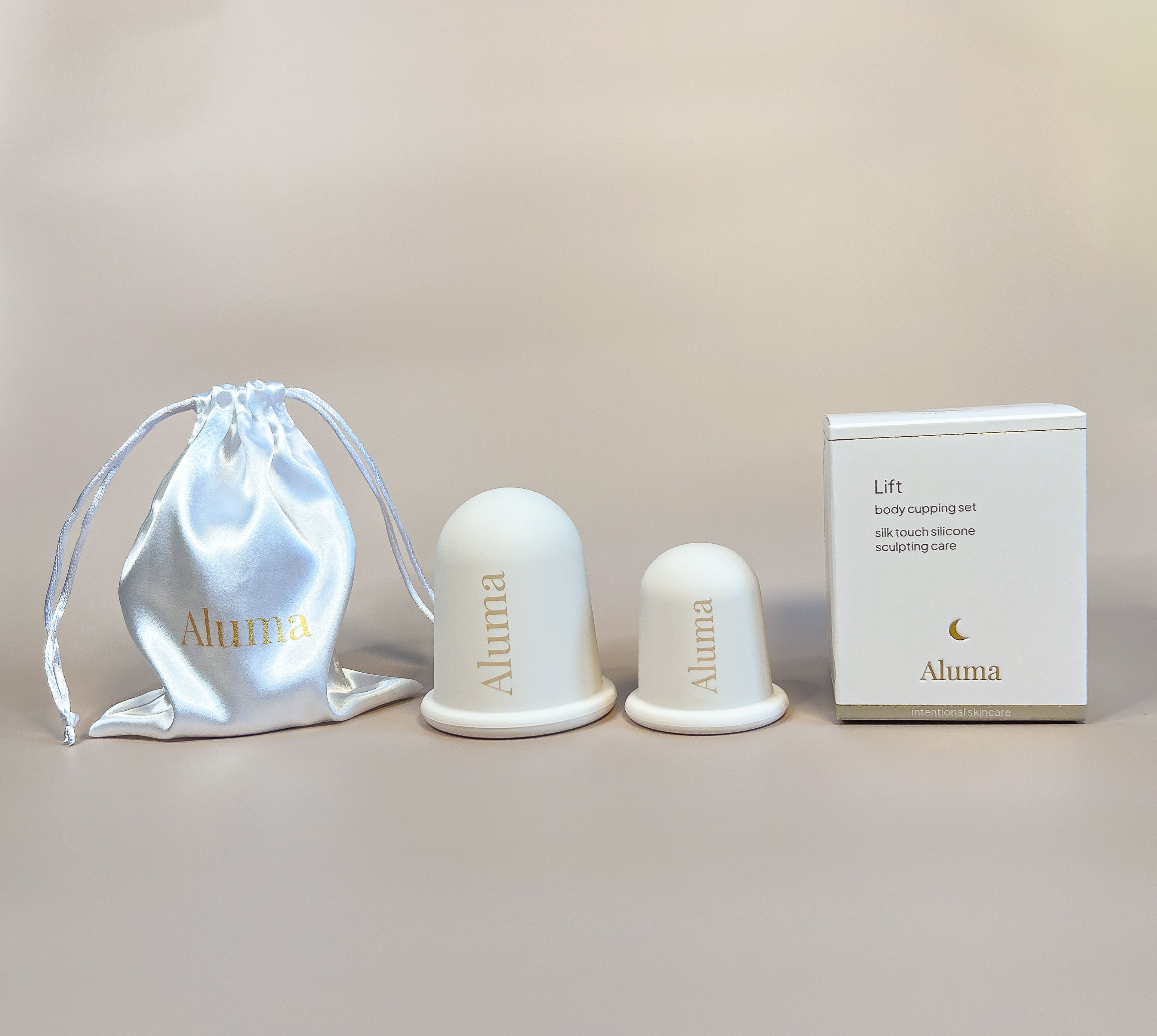 Aluma Lift body cupping sæt med to silikonekopper til krop, hvid satinpose og gaveæske på beige baggrund