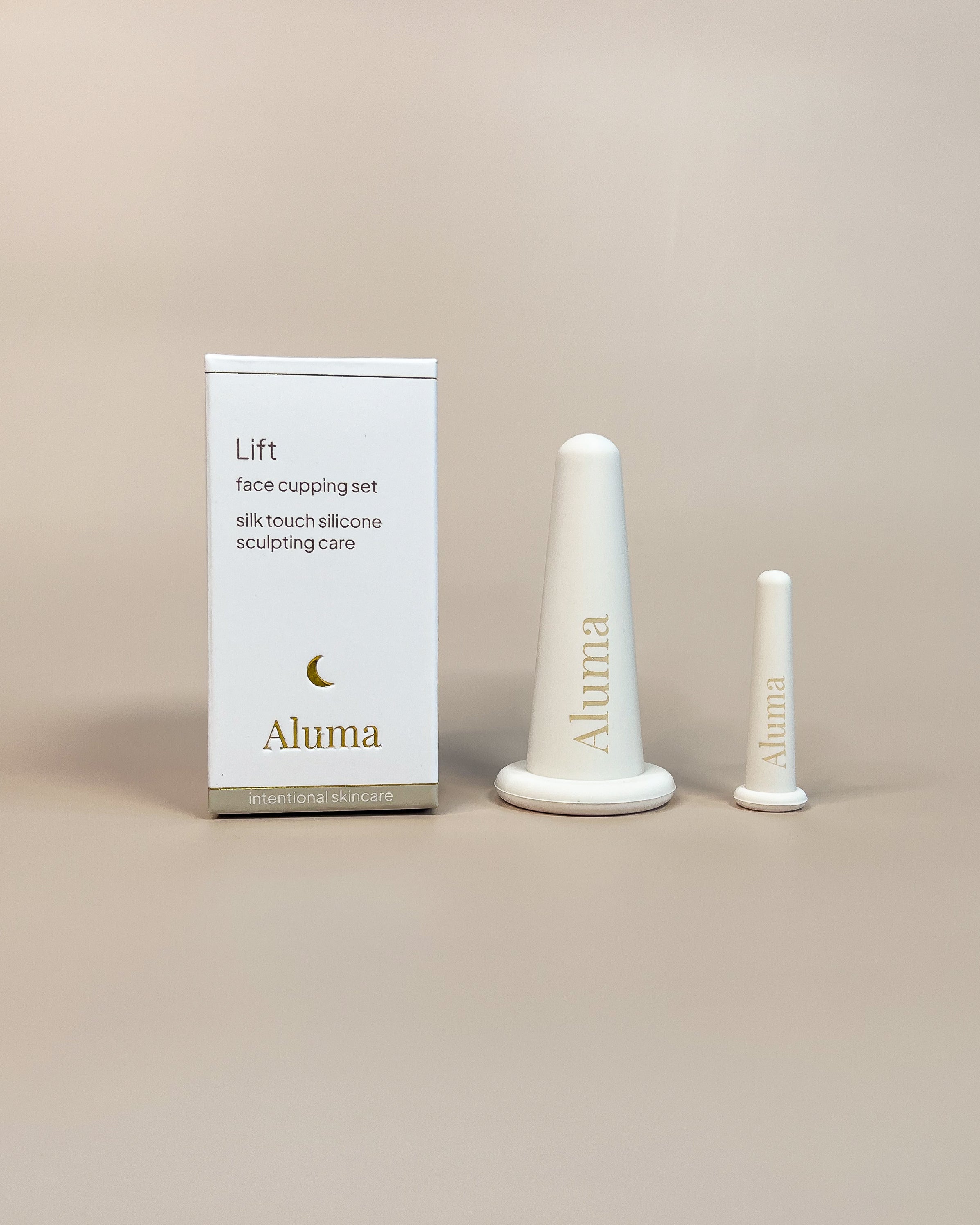Aluma Lift face cupping sæt med to silikonekopper til ansigtet og hvid emballageæske på beige baggrund